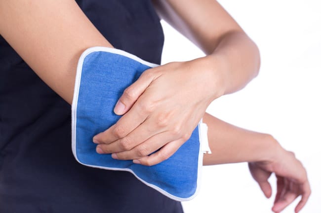 Woman putting an ice pack on her elbow pain